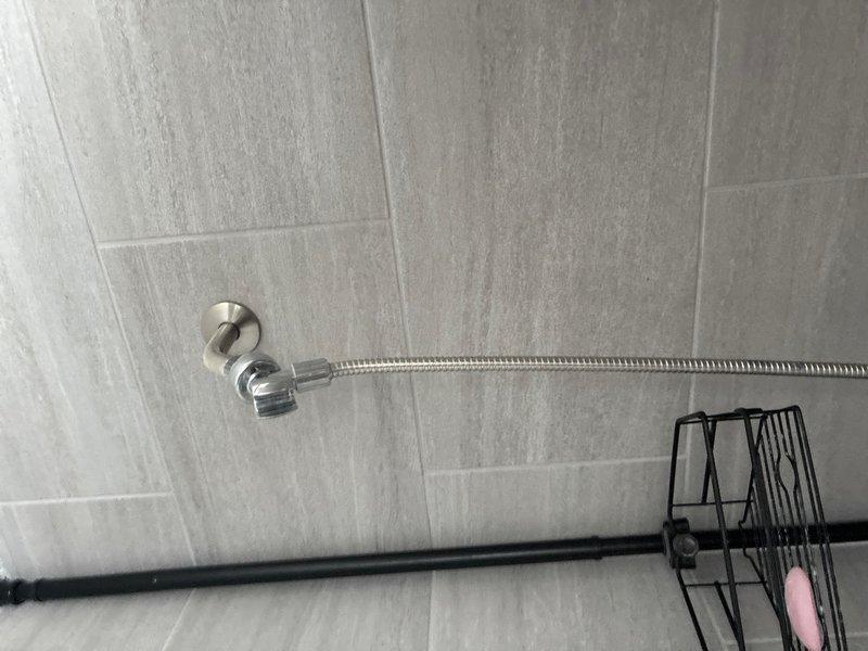 Completed routine plumbing maintenance inspection of residential water heater and shower fixtures. Documented significant corrosion and mineral buildup on water heater pipe connections and fittings, particularly around brass connections with blue valve assembly. Verified shower installation with chrome fixtures and handheld shower assembly functioning properly.