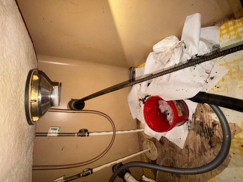 Responded to a recurring main drain backup in the basement, previously serviced two months prior. Performed cleanout of the main drain line to restore proper drainage and flow. Documented existing conditions including under-sink plumbing connections and HVAC ductwork in the service area for reference.