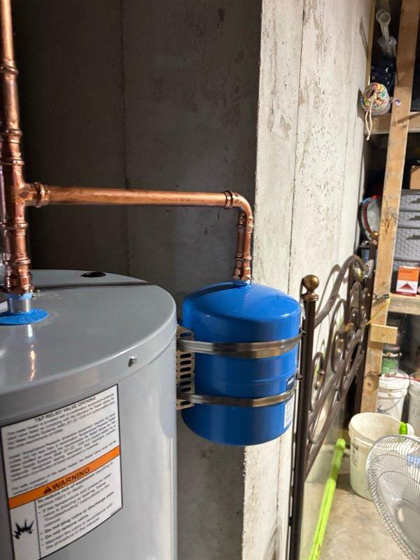 Installed a new 50-gallon gas water heater in basement utility area with thermal expansion tank to protect against pressure buildup in the closed plumbing system. Retrieved and installed extended warranty kit from supply house, upgrading the manufacturer's tank warranty from 6 years to 10 years. Connected all copper supply lines, yellow flexible gas line, and properly secured the thermal expansion tank to the wall with metal strapping, ensuring all components meet code requirements and safety standards.