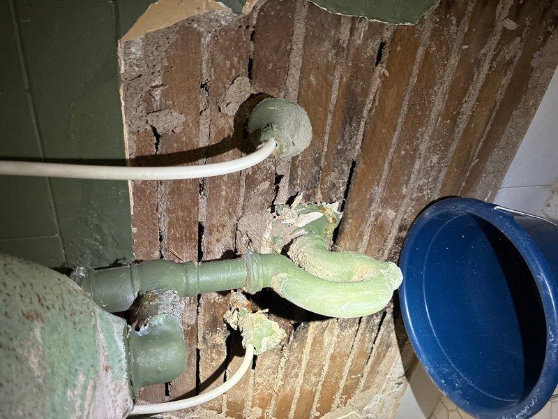 Completed plumbing estimate for bathroom sink replacement on main floor. Upon inspection, identified deteriorated piping infrastructure behind wall with compromised wall surface exposing wooden studs and aged copper supply lines. Assessed existing plumbing system including corroded pipe connections, worn galvanized fittings, and degraded piping materials showing signs of long-term water exposure. Documented conditions of accessible piping in crawl space area and behind damaged wall section, noting multiple connection points requiring replacement. Photographed current installation to provide comprehensive assessment for complete under-sink plumbing replacement including supply lines, drain assembly, and necessary wall repairs.