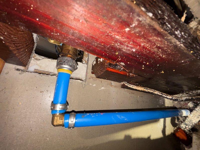 Responded to reported leak in wall concern. Conducted thorough inspection of accessible plumbing areas, including crawlspace beneath affected room and interior wall cavity. Located blue PVC drainage piping with compression fittings secured to floor joists, showing signs of moisture exposure on surrounding wooden structural members with visible staining and discoloration. Identified significant water damage and deterioration at interior wall corner with dark staining indicative of active or previous moisture intrusion. Documented conditions with photographs for reference and further assessment recommendations.