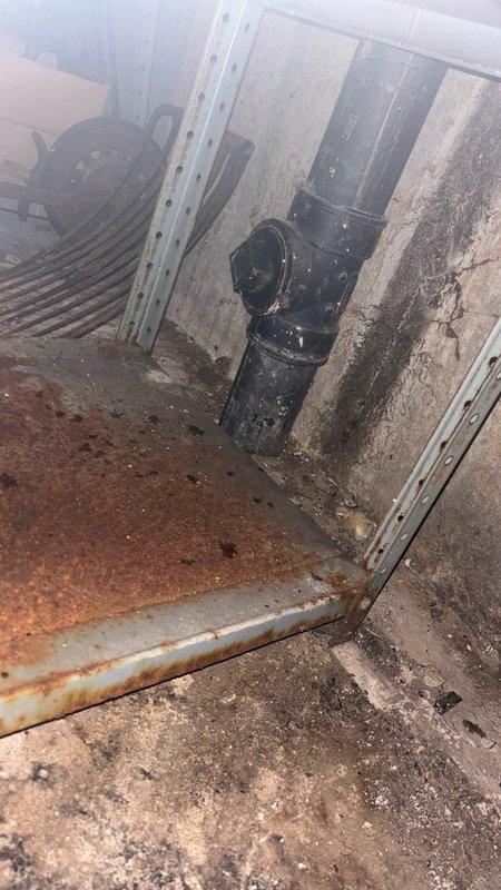 Performed camera inspection of plumbing system in basement utility area. Visual documentation captured condition of vertical drain pipe, surrounding concrete block walls showing moisture damage and deterioration, and floor conditions with visible rust and water exposure indicators.