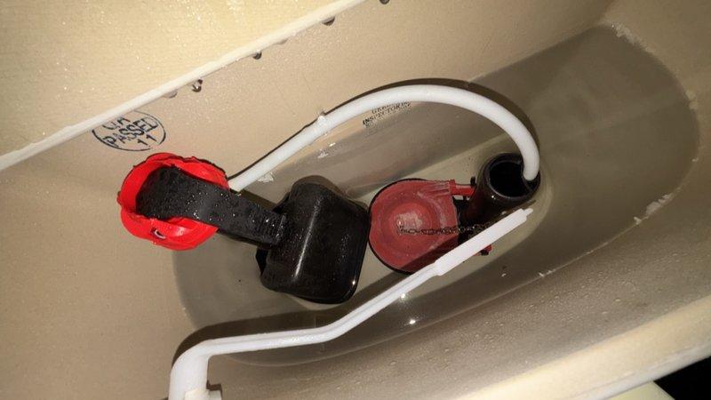 Completed comprehensive whole home plumbing inspection. Examined toilet tank components including flapper valve assembly with float mechanism, fill valve, overflow tube, and flush chain—all components found in functional condition with minor mineral deposits noted. Inspected ceiling-mounted plumbing access panel revealing organized installation of braided stainless steel water supply lines with shut-off valves and corrugated drain lines, all properly secured and accessible for future maintenance.