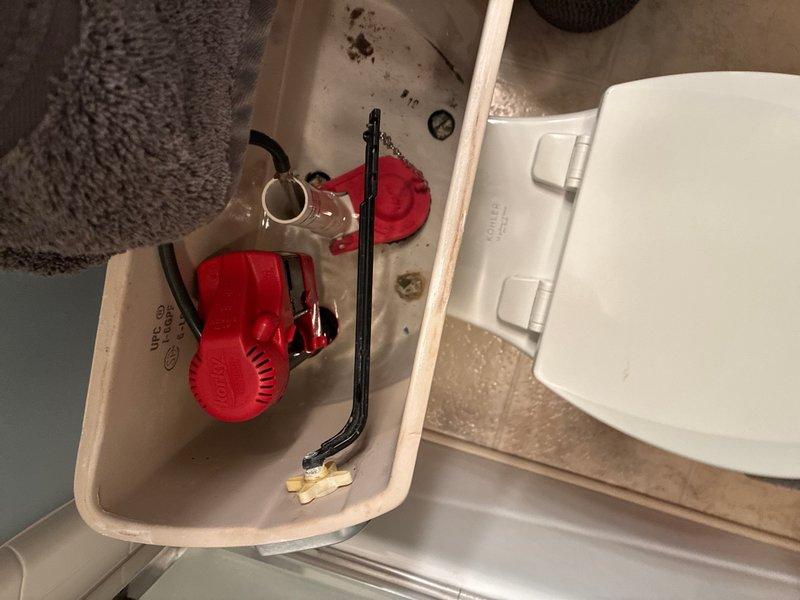 Completed toilet repair in lower level bathroom of 25-year-old residence. Inspected toilet tank components and identified worn flush valve assembly with deteriorated flapper requiring replacement. Observed mineral deposits and debris accumulation on tank bottom indicating water quality issues. Evaluated water treatment system consisting of dual water softener/filtration tanks with Duonics equipment. Checked system pressure gauges, copper supply lines, and brass valve fittings for proper operation. Replaced faulty flapper and adjusted float mechanism to restore proper flush function and prevent running water. Recommended ongoing maintenance of water treatment system to address mineral buildup and extend plumbing fixture lifespan.