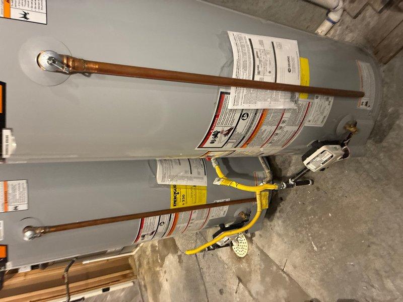 Completed installation of two 50-gallon gas-fired water heaters in a residential utility space. Mounted both units vertically on concrete floor and established all necessary plumbing connections using copper piping with brass drain valves and shutoff controls. Installed thermal expansion tank to protect against excessive pressure buildup in the closed plumbing system. Connected yellow flexible gas lines to both units with appropriate black iron fittings and shutoff valves. Installed temperature and pressure relief valves on each water heater with proper discharge piping. Verified all connections for leaks, tested gas line integrity, and confirmed proper venting configuration. System is fully operational and ready for service.