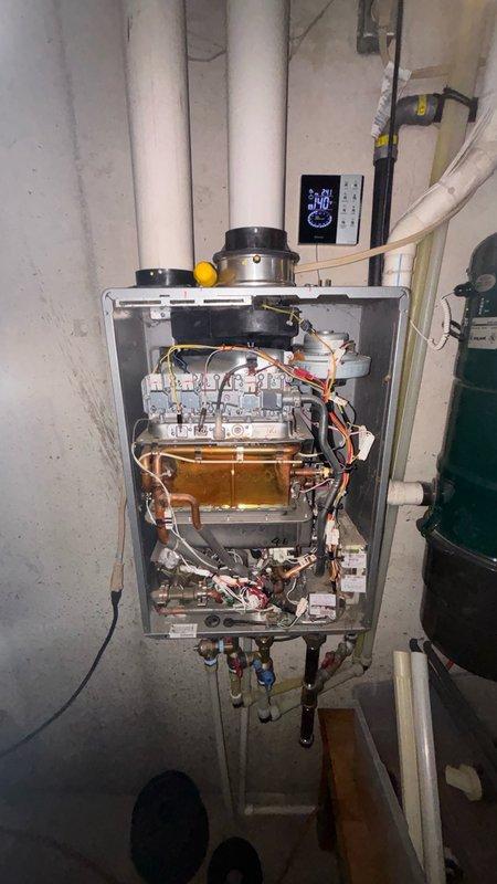 Responded to tankless water heater displaying error code 11. Upon arrival, accessed unit interior by removing front cover panel and performed diagnostic inspection of internal components including heat exchanger, combustion chamber, electrical connections, and venting system. Error code 11 typically indicates ignition failure or flame detection issues. Inspected burner assembly, flame sensor, gas supply connections, and verified proper venting configuration through exhaust pipe system. Examined all electrical terminal blocks and wiring connections for secure contact. Checked control board functionality and digital display panel readings. Verified water flow sensors, shut-off valves, and supply line connections at base of unit were operating within specifications. Documented system condition through photographic evidence showing internal mechanical components, heat exchanger assembly, copper piping network, PVC venting configuration, and control interface.