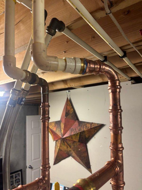 Completed installation of 50-gallon gas water heater with thermal expansion tank in residential basement utility area. Configured hot and cold water supply lines using combination of copper piping and color-coded PEX tubing (red for hot, blue for cold) with appropriate brass fittings and connections. Installation includes proper venting, gas line connection, and integration with existing plumbing infrastructure including exposed ceiling-mounted distribution system.
