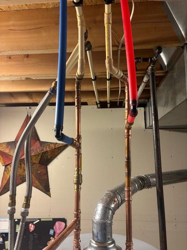 Completed installation of 50-gallon gas water heater with thermal expansion tank in residential basement utility area. Configured hot and cold water supply lines using combination of copper piping and color-coded PEX tubing (red for hot, blue for cold) with appropriate brass fittings and connections. Installation includes proper venting, gas line connection, and integration with existing plumbing infrastructure including exposed ceiling-mounted distribution system.