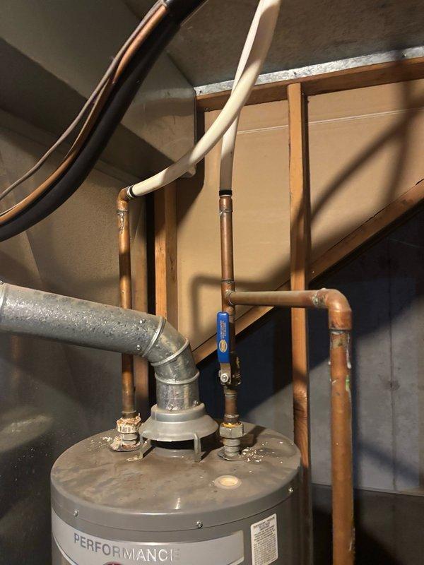 Responded to reported leak on gas-fired tanked water heater in basement. Upon inspection, identified active leak requiring immediate attention. Performed diagnostic assessment of unit and associated plumbing connections, including evaluation of pressure relief valve, supply lines, and tank integrity. Documented existing system configuration showing Performance-brand water heater with copper supply piping, blue-handled isolation valve, and PVC venting. Verified system pressure readings using calibrated gauge. Completed necessary repairs to resolve leak condition and restore proper operation. Tested all connections for integrity post-repair and confirmed system returned to normal operating parameters with no further water discharge observed.