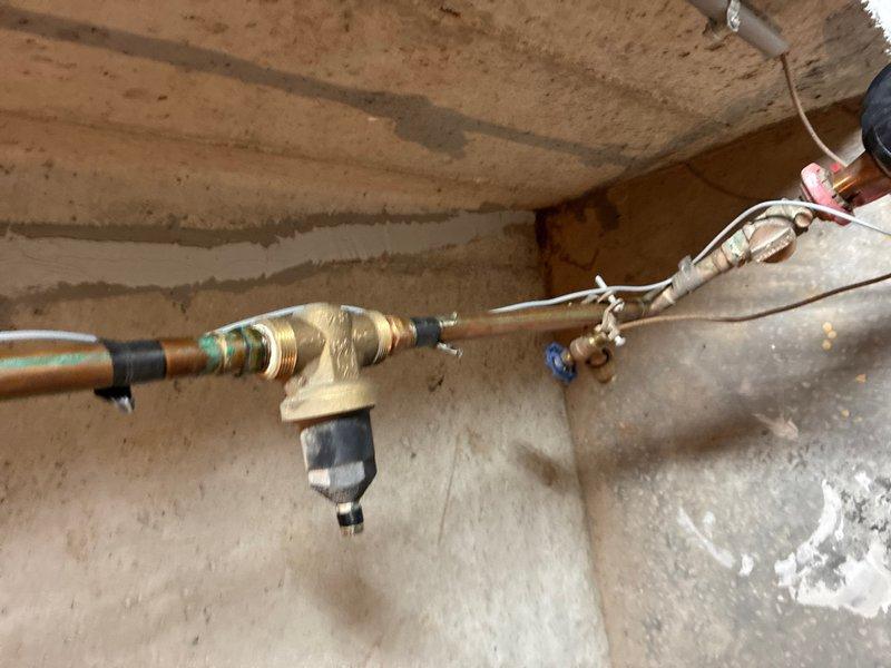 Responded to service call for intermittent water drip from pressure relief valve on tanked water heater in basement of 26-year-old residence. Upon inspection, examined all plumbing connections, copper piping, brass fittings, and pressure relief valve assembly mounted on the water heater. Found no active leaking at time of arrival, which is consistent with reported intermittent nature of the issue. Verified that minor weeping from temperature and pressure relief (TPR) valve can occur during normal thermal expansion cycles, particularly when water is heated and expands within the tank. Inspected expansion tank mounted on wall to confirm proper operation and air charge. Checked all visible plumbing connections including inlet and outlet pipes, valve assemblies, and mounting hardware for signs of deterioration or improper installation. Documented current condition of water heater installation with photographic evidence showing copper supply lines, brass fittings, blue-handled isolation val