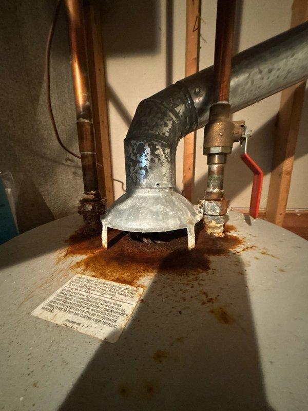 Performed assessment of non-functional 50-gallon gas water heater located in basement. Unit was over 20 years old and required complete replacement. Inspection revealed significant corrosion on top-mounted pipe connections with heavy rust staining across the appliance surface. Deteriorated elbow fittings and corroded piping connections indicated extensive wear from age and moisture exposure. Documented existing copper supply lines, gas connections, and venting system configuration. Provided estimate for replacement of tanked gas water heater with comparable 50-gallon capacity unit, including removal of existing appliance and installation of new equipment with proper venting and code-compliant connections.