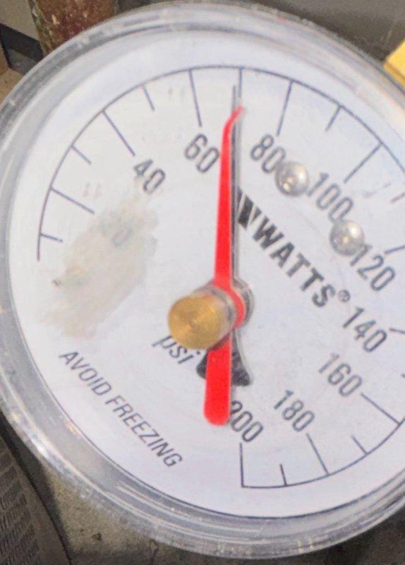 Performed plumbing maintenance inspection in crawl space area, evaluating system pressure via water pressure gauge reading and documenting current mechanical infrastructure conditions. Verified proper PSI levels on pressure regulator and assessed overall plumbing system accessibility and component placement beneath structure.