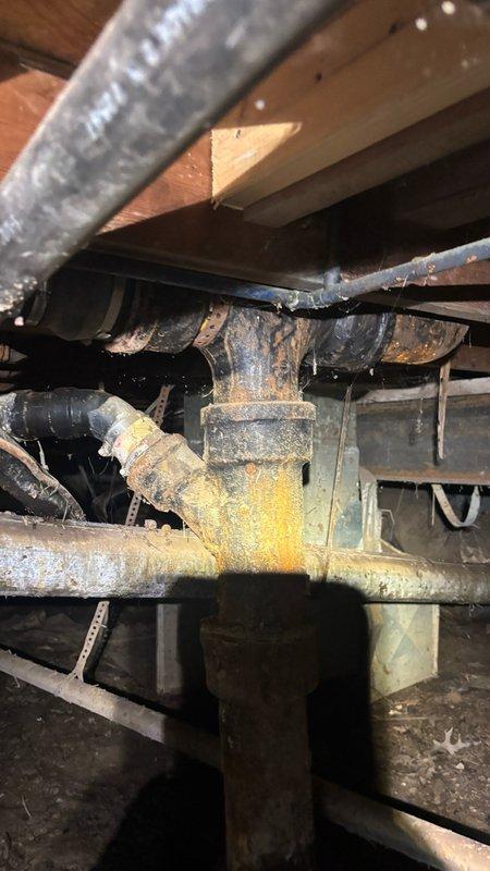 Responded to main drain line blockage caused by root intrusion. Located cleanout access point at exterior crawl space entry beneath structure. Successfully cleared root mass from main drain line using mechanical auger equipment. Verified proper flow restoration through drainage system. Documented existing corrosion on exposed plumbing components in crawl space area for future reference.