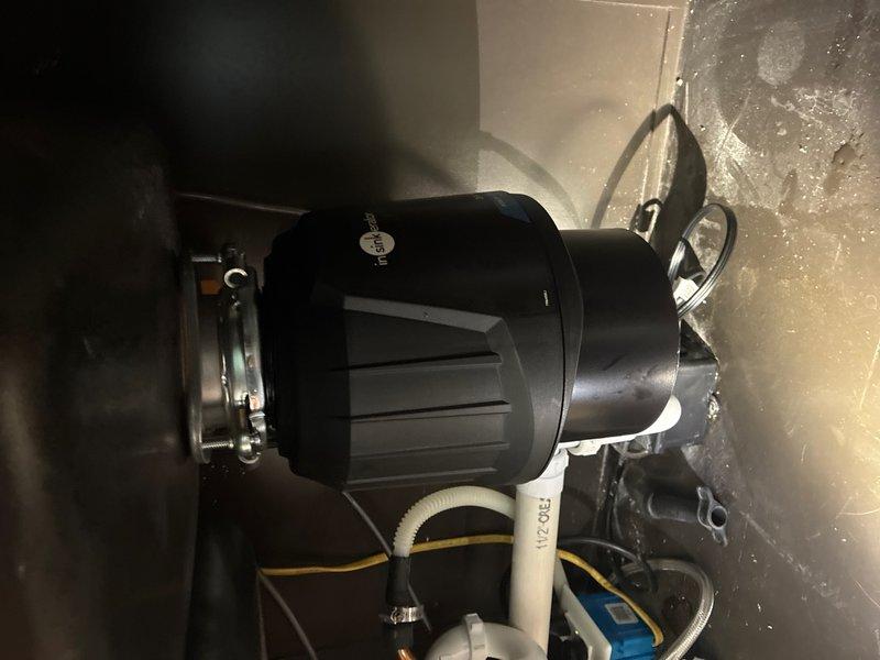 # Garbage Disposal Installation

Responded to service call for garbage disposal installation in residential kitchen. Upon arrival, assessed existing plumbing configuration under sink to ensure compatibility with new disposal unit. Disconnected existing drain lines and prepared mounting assembly for installation.

Installed new garbage disposal unit to sink flange using manufacturer-specified mounting ring and hardware. Connected discharge drain line to existing P-trap assembly with proper sealing to prevent leaks. Verified electrical connections were secure and complied with local electrical codes. Tested unit operation through multiple cycles to confirm proper grinding function and drainage flow. Inspected all connections for leaks and verified no water seepage at mounting points or drain connections. Unit operating within normal parameters upon completion.