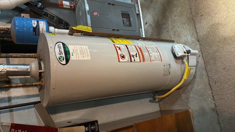 Responded to service call for non-functioning water heater in unfinished basement of older residential property. Upon arrival, inspected A.O. Smith tanked water heater unit and associated plumbing connections, including copper supply lines, pressure relief valve, and yellow flexible gas line. Evaluated water treatment system and electrical panel in proximity to unit. Diagnosed issue, performed necessary repairs to restore proper operation, and verified all safety labels and warning indicators were visible and intact. Unit returned to full working condition with all connections secure and system operating within manufacturer specifications.