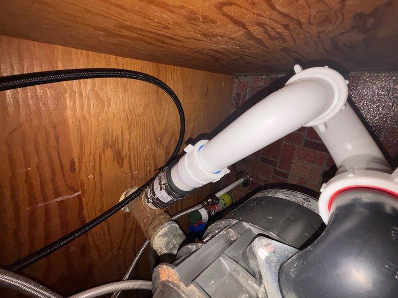 Responded to leak complaint under kitchen sink in drain system. Upon inspection, located leak at P-trap connection point beneath sink cabinet. Observed compromised seal at PVC P-trap fitting with visible moisture present. Inspected associated drain lines and supply connections in adjacent crawl space area to verify leak source and assess extent of water intrusion. Documented plumbing configuration including P-trap assembly, flexible supply lines, and connection points for service records.
