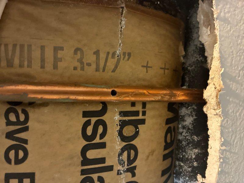 Responded to emergency water leak in basement bathroom caused by accidental pipe penetration during medicine cabinet installation. Upon arrival, assessed damage and located compromised copper water supply line within wall cavity. Created access opening in drywall to expose affected plumbing section. Found punctured copper pipe running horizontally through wall between fiberglass insulation, with active leak point clearly visible. Shut off water supply to affected area and drained remaining water from damaged line. Cut out compromised section of copper pipe and prepared pipe ends for repair. Installed new copper pipe section using soldered joints on both connections to ensure watertight seal. Pressure tested repair to verify integrity of soldered connections and confirm no additional leaks present. Restored water supply and conducted final inspection to ensure proper flow and system operation.