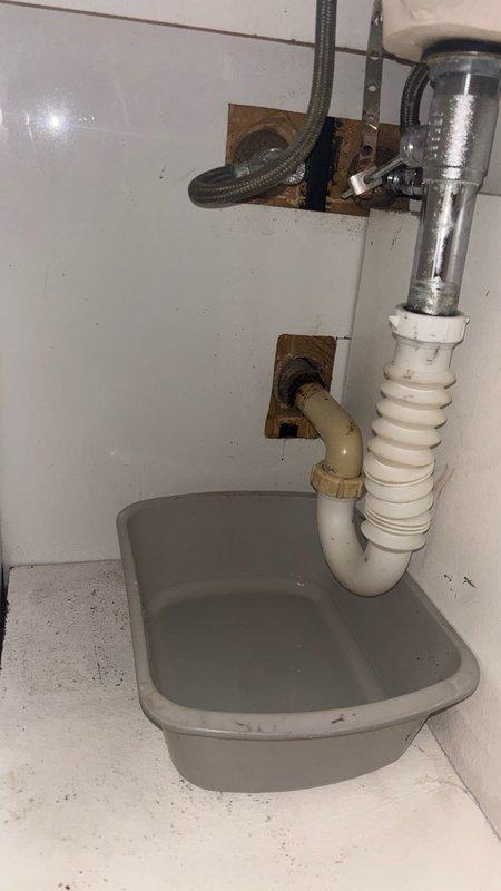 Responded to bathroom sink with reported drainage issues and leak beneath the fixture. Upon inspection, found corroded P-trap assembly and deteriorated drain connections causing both the blockage and leak. Customer had previously attempted to clear the drain with chemical drain cleaner multiple times, which contributed to the deterioration of the plastic components. Removed and replaced the defective P-trap assembly with new white plastic P-trap and corrugated flexible drain pipe. Installed gray drip basin beneath the plumbing assembly to protect cabinetry. Tested the drain system for proper flow and verified all connections were secure with no leaks present.