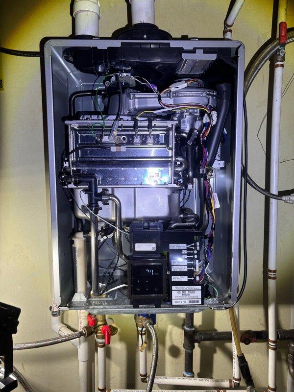 Completed preventative plumbing maintenance inspection on residential property. Accessed attic crawl space to inspect drainage system including PVC trap configuration and verified proper installation and labeling of all plumbing lines. Inspected tankless water heater unit, removed front cover panel to examine internal components including heat exchanger assembly, control board, electrical connections, and verified all inlet/outlet plumbing connections and shut-off valves are functioning properly.
