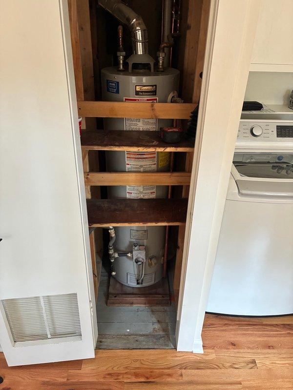 Conducted on-site assessment of 20-year-old Kenmore slim water heater located in basement utility closet. Unit currently operational but homeowner requested preventative replacement estimate following recent property purchase. Inspected existing installation including inlet/outlet plumbing connections, copper supply lines with shutoff valves, metallic flue pipe configuration, and overall equipment condition within confined closet space. Documented equipment specifications, mounting configuration, and surrounding plumbing infrastructure to provide accurate replacement recommendations and pricing for slim-profile water heater suitable for tight installation space.