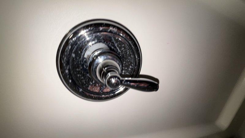 Completed comprehensive whole home plumbing inspection examining all accessible fixtures and components. Documented condition of bathroom fixtures including shower valve assembly with chrome finish showing mineral deposit accumulation and water spotting, and porcelain sink with single-lever chrome faucet, verifying proper drainage function through main and overflow drain openings.