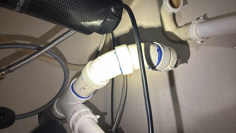 Responded to service call for disconnected drainage pipe at garbage disposal unit. Upon inspection, found the discharge pipe had separated from the disposal's drain outlet connection. Reattached and secured the PVC drainage pipe to the disposal mounting flange using proper compression fittings. Verified all connections were tight and leak-free, tested the disposal operation, and confirmed proper drainage flow through the P-trap assembly.