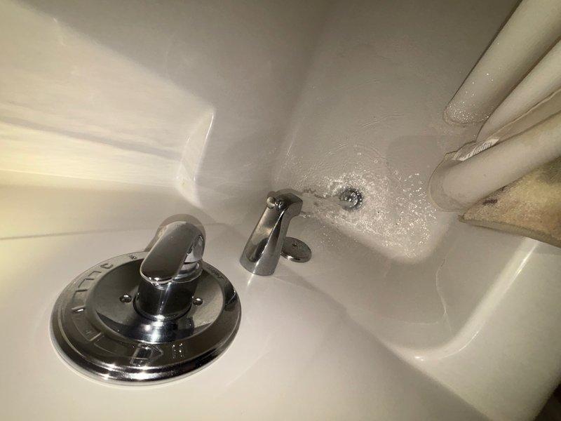 Completed plumbing maintenance visit inspecting bathroom fixtures and mechanical room equipment. Examined bathroom sink, faucet assembly, and visible plumbing connections, noting proper drainage and water supply function. Inspected heating unit with tankless water heating system in mechanical room, verifying copper and PVC piping connections, condensate drainage, and proper ventilation ducting.