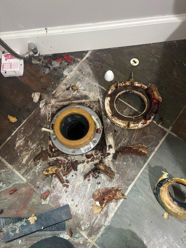 Performed comprehensive whole-home plumbing inspection on residential property. Examined all accessible plumbing fixtures, supply lines, drain systems, and water heater components throughout the home.

Inspected bathroom facilities and identified deteriorated toilet flange with significant rust and corrosion on metal components. Documented compromised wax ring seal with visible debris and deteriorated sealing materials present on bathroom floor. Flange installation showed signs of age-related degradation requiring attention to prevent future leaks and ensure proper fixture stability.

Examined basement utility areas and documented copper supply piping conditions along ceiling joists. Noted moisture staining patterns on concrete floor surfaces indicating potential historical water intrusion or condensation issues. Observed floor crack in concrete slab foundation. Assessed pipe mounting hardware and support brackets for proper installation and structural integrity.

Evaluated all visible