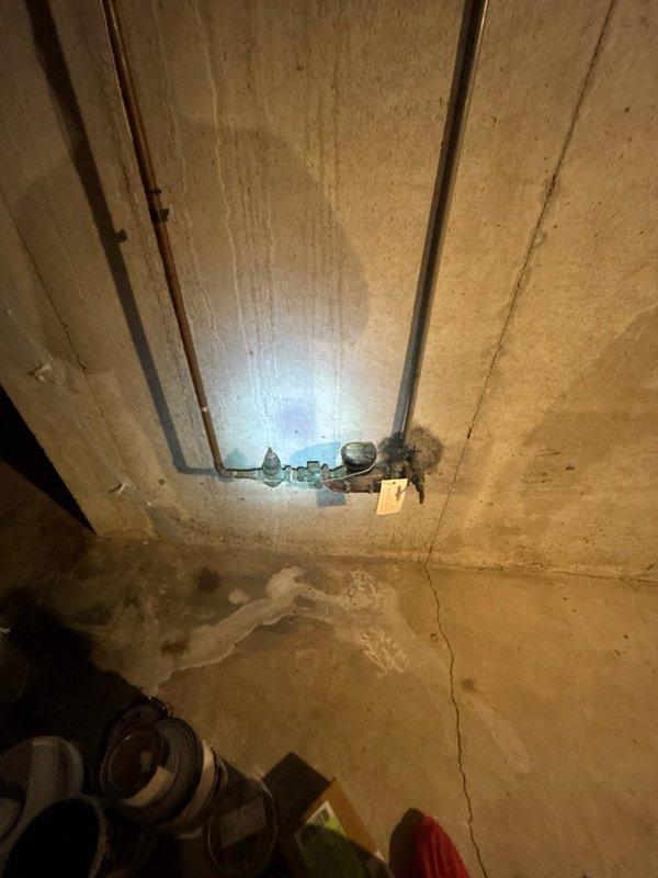 Performed comprehensive whole-home plumbing inspection on residential property. Examined all accessible plumbing fixtures, supply lines, drain systems, and water heater components throughout the home.

Inspected bathroom facilities and identified deteriorated toilet flange with significant rust and corrosion on metal components. Documented compromised wax ring seal with visible debris and deteriorated sealing materials present on bathroom floor. Flange installation showed signs of age-related degradation requiring attention to prevent future leaks and ensure proper fixture stability.

Examined basement utility areas and documented copper supply piping conditions along ceiling joists. Noted moisture staining patterns on concrete floor surfaces indicating potential historical water intrusion or condensation issues. Observed floor crack in concrete slab foundation. Assessed pipe mounting hardware and support brackets for proper installation and structural integrity.

Evaluated all visible