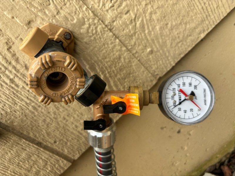 Completed comprehensive plumbing inspection of residential property. Inspected under-sink plumbing assembly including chrome drain with threaded connections, dual flexible supply lines with metal fittings, and white PVC P-trap configuration, confirming proper installation and functionality. Examined pressure gauge assembly with brass valve body, flexible metal braided hose, and circular dial gauge displaying appropriate pressure readings. All plumbing components, connections, and fixtures found to be in satisfactory working condition with no visible leaks or immediate concerns identified.