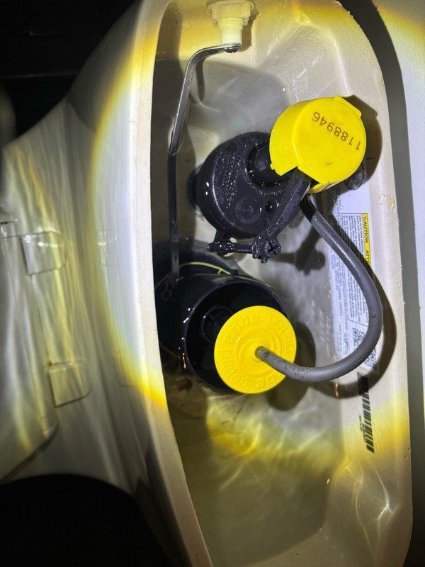 Performed plumbing maintenance inspection and servicing of toilet system components. Inspected and documented dual flush valve assembly with yellow actuator caps, verified proper operation of internal tank mechanisms including fill valve, flapper assembly, and overflow tube. Also inspected sump pump basin installation, confirming proper placement of pump unit within discharge media and verifying electrical connections and float switch operation.