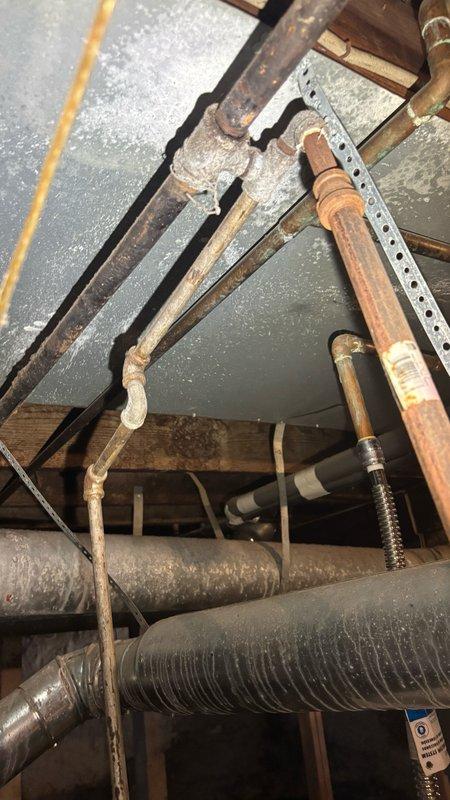 Conducted on-site evaluation for tankless water heater installation. Assessed existing plumbing infrastructure in attic space, documenting current copper supply lines with visible corrosion and patina buildup, HVAC ductwork configuration, and structural access points through wooden beam framework and brick wall penetrations. Photographed existing piping conditions including corroded vertical copper lines, flexible ductwork, and utility routing to determine feasibility and requirements for tankless water heater conversion. Provided comprehensive quote for tankless water heater system replacement based on site assessment findings.