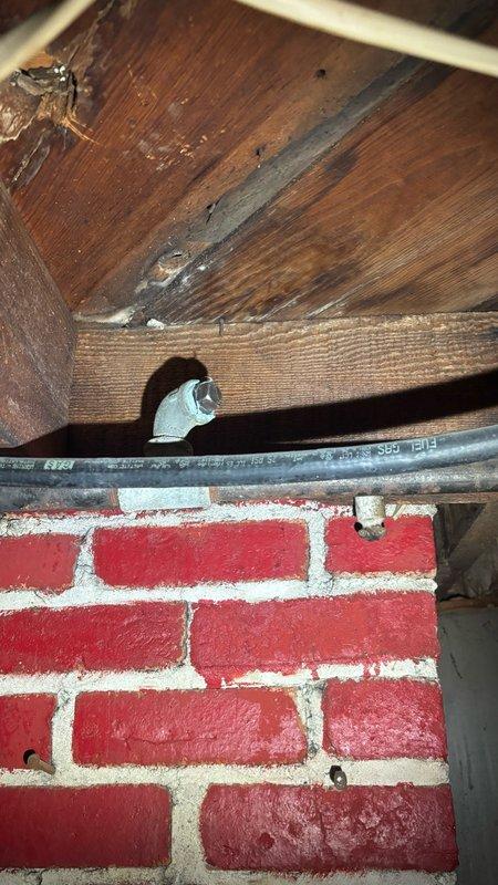 Conducted on-site evaluation for tankless water heater installation. Assessed existing plumbing infrastructure in attic space, documenting current copper supply lines with visible corrosion and patina buildup, HVAC ductwork configuration, and structural access points through wooden beam framework and brick wall penetrations. Photographed existing piping conditions including corroded vertical copper lines, flexible ductwork, and utility routing to determine feasibility and requirements for tankless water heater conversion. Provided comprehensive quote for tankless water heater system replacement based on site assessment findings.