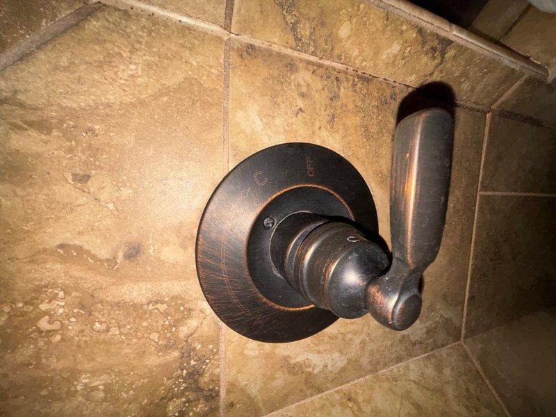 Completed comprehensive plumbing inspection as part of promotional service offering. Examined shower valve assemblies in two separate bathroom locations, documenting conditions through photographic evidence. First inspection area revealed oil-rubbed bronze shower valve and trim mounted on large format tile surround, with visible water staining and mineral deposit accumulation on tile surfaces around fixtures. Second inspection area showed chrome-plated shower control valve with significant hard water buildup and mineral spotting on fixture surfaces, requiring attention to prevent deterioration of finish and potential operational issues.