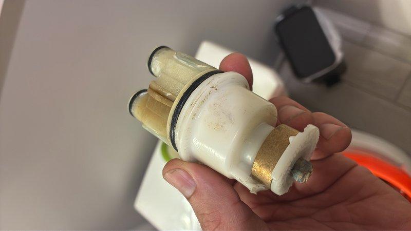 Responded to emergency call for continuous water flow from shower that would not shut off. Upon inspection, identified failed cartridge valve as the source of the problem. Removed deteriorated cartridge showing significant mineral buildup and corrosion on brass stems and O-ring failure. Installed replacement cartridge valve and tested operation to confirm proper shut-off function restored.