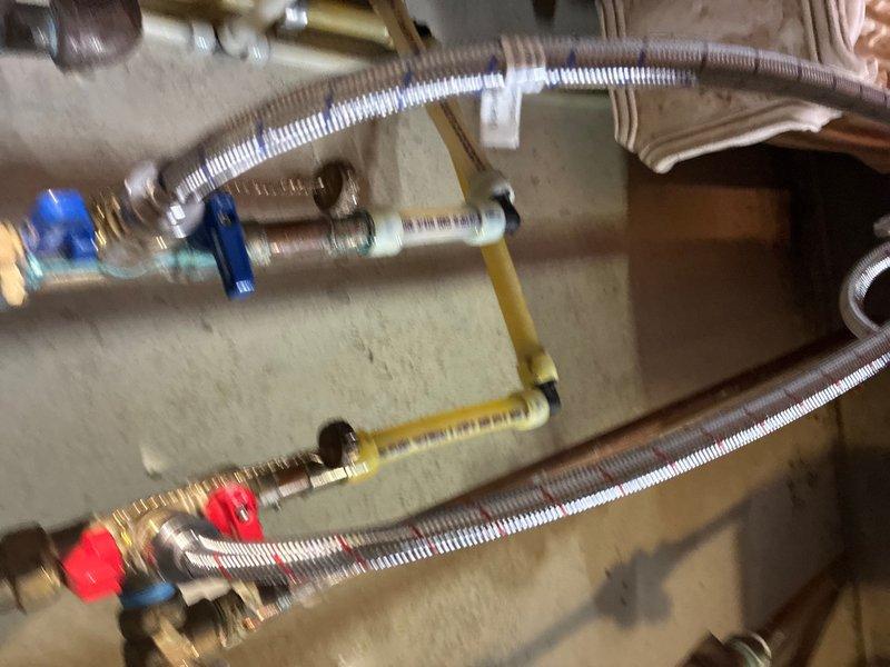 Completed plumbing maintenance inspection and system evaluation. Inspected tankless water heater installation including water supply lines, gas connections, shut-off valves, and flexible braided stainless steel supply hoses. Verified proper operation of blue and red-handled ball valves, brass fittings, and manifold connections. Tested exterior water pressure using gauge, confirming system pressure within normal operating parameters. All components found in functional condition with no leaks detected.