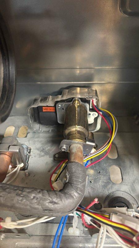 Completed installation of replacement water flow sensor and sensor assembly on tankless water heater unit. Removed failed flow sensor valve assembly and installed new component featuring brass valve body with integrated electronic flow detection system. The replacement assembly includes solenoid actuator with multi-wire harness connection and manual override lever for emergency operation. Properly seated the valve into the unit's compartment, secured all mounting hardware, and reconnected color-coded electrical wiring to the main control board using factory connectors. Verified proper wire routing to prevent interference with other components and ensured all connections were secure. Tested flow sensor operation and confirmed unit functionality upon completion.
