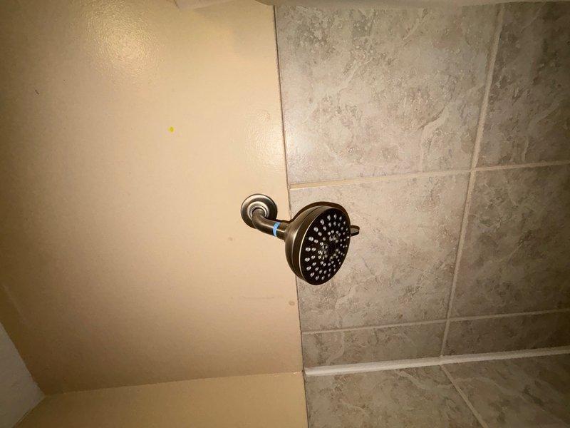 Completed installation of customer-provided bathroom fixtures in main level bathroom of split-level home. Installed new chrome tub spout and oil-rubbed bronze showerhead assembly with curved wall-mounted arm, replacing existing fixtures. Verified proper water flow, tested for leaks, and confirmed all connections were secure upon completion.