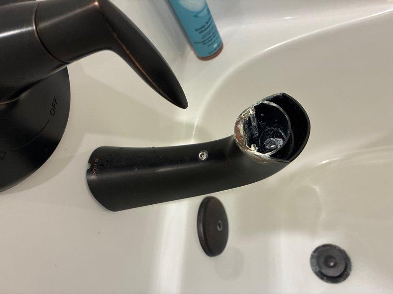 Responded to guest bathroom service call for malfunctioning tub/shower faucet. Upon inspection, discovered the bathroom sink faucet spout had become detached from its mounting post, with visible corrosion and mineral buildup on the internal connection hardware. Disassembled the black faucet components to assess the extent of deterioration on the mounting mechanism and connecting points. Documented the condition of the fixtures showing significant wear, tarnishing, and mineral deposits around the spout opening and internal hardware that contributed to the failure. Provided assessment and repair recommendations for proper fixture restoration.