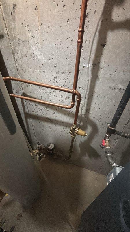 Completed comprehensive plumbing inspection to address concerns regarding water usage and potential leak detection. Performed visual assessment of all accessible plumbing fixtures, supply lines, and drainage systems throughout the property. Inspected exterior pressure gauge and hose connection points for signs of leakage or abnormal pressure readings. Examined basement utility area plumbing infrastructure, including copper water supply lines, PVC drainage pipes, shutoff valves, and connection fittings mounted to concrete wall. Evaluated water heater installation, associated piping configuration, and brass valve assemblies for proper operation and potential leak sources. Documented system conditions with photographic evidence showing pressure monitoring equipment and plumbing distribution network. No active leaks identified during inspection period. All visible pipe connections, joints, and valve assemblies appeared secure with no signs of moisture, corrosion, or water damage on surroun