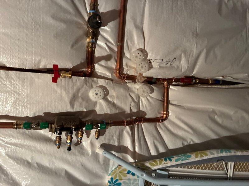 Completed comprehensive whole home plumbing inspection examining all accessible water supply lines, pressure regulation systems, and distribution manifolds. Documented exterior hose bib assembly with ProFlo pressure gauge reading and gate valve operation, plus interior copper manifold system with multiple zone valves and shutoff controls in proper working condition.
