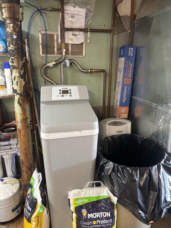 Responded to service call for non-operational tankless water heater. Upon arrival, conducted comprehensive diagnostic inspection of the water heating system and associated plumbing infrastructure. Examined exterior venting components, including PVC exhaust piping and louver vent installation to verify proper combustion air flow and exhaust discharge. Inspected interior utility area where water treatment equipment, including active water softener unit with copper supply lines, was noted in proximity to the water heating system. Evaluated all visible plumbing connections, supply lines, and system integration points. Documented existing conditions through photographic records showing exterior vent configuration and interior utility space layout for service records and repair recommendations.