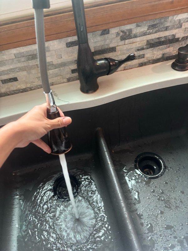 Responded to a no water condition isolated to the kitchen sink while all other fixtures in the home maintained normal water pressure. Upon inspection, found the kitchen faucet aerator and spray head were severely clogged with mineral deposits and debris, restricting water flow. Disassembled the pull-down spray faucet, cleaned internal components, and cleared all blockages. Tested water flow and spray function to verify full restoration of water pressure and proper operation. Also addressed a slow-draining kitchen sink by plunging the drain to clear a partial obstruction, restoring proper drainage function to both basins of the double sink.