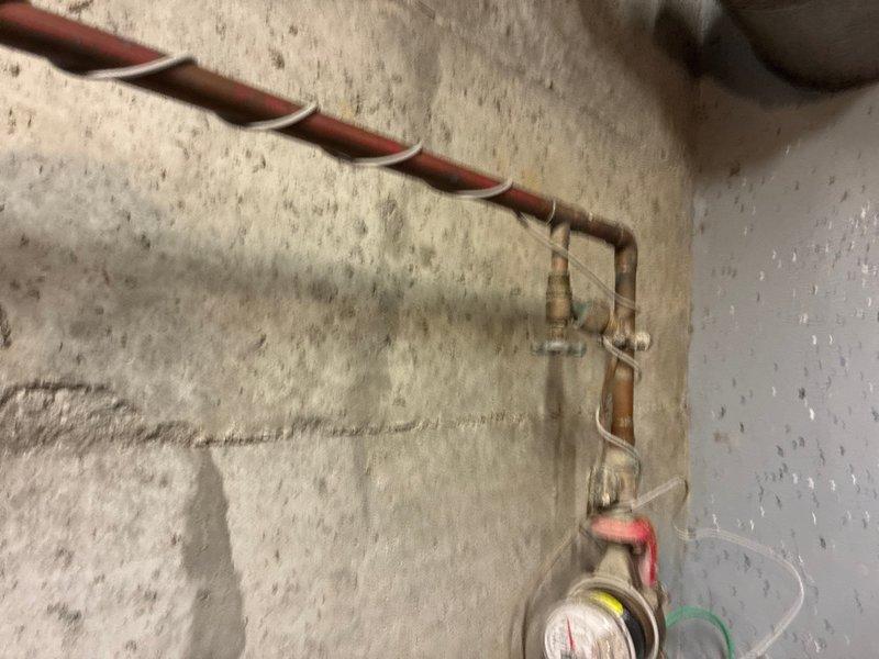 Completed comprehensive whole home plumbing inspection of residential property. Inspected and documented HVAC refrigerant lines with helical insulation wrapping, pressure gauges, and copper connection fittings mounted on interior wall—all components found to be properly installed with secure connections. Examined kitchen plumbing installation including stainless steel double-basin sink, pull-out faucet assembly, water supply valve connections, and drainage system—all fixtures operational with no visible leaks or deficiencies noted.