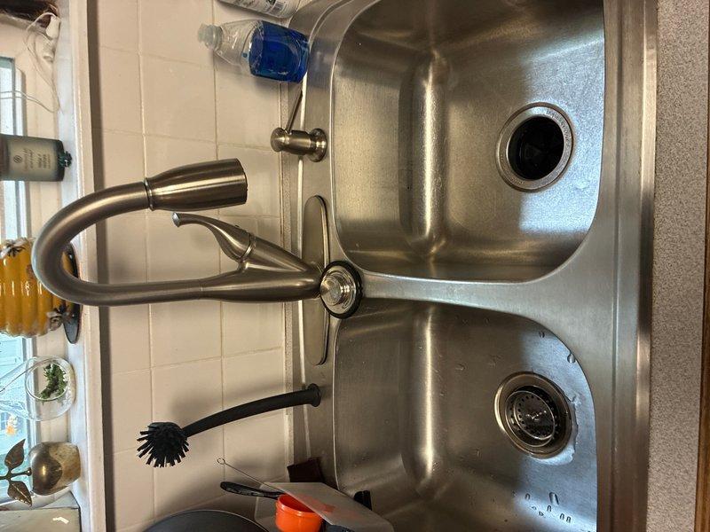 Completed comprehensive whole home plumbing inspection of residential property. Inspected and documented HVAC refrigerant lines with helical insulation wrapping, pressure gauges, and copper connection fittings mounted on interior wall—all components found to be properly installed with secure connections. Examined kitchen plumbing installation including stainless steel double-basin sink, pull-out faucet assembly, water supply valve connections, and drainage system—all fixtures operational with no visible leaks or deficiencies noted.