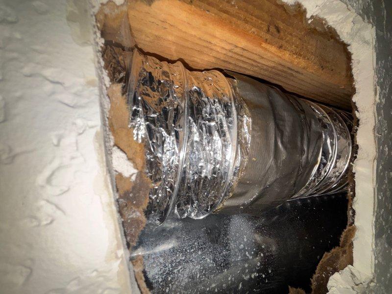 Responded to water leak investigation in basement of 21-year-old residential property. Upon arrival, conducted thorough visual inspection to locate source of reported moisture intrusion. Discovered active water leak affecting HVAC ductwork penetration through basement wall assembly. 

Investigation revealed significant water infiltration at flexible aluminum duct pass-through, with heavy water staining and dripping evident on ductwork surface and surrounding wooden framing members. Dark water staining patterns indicated prolonged exposure to moisture. White mineral deposits and brown discoloration observed on structural wood members at penetration point, consistent with extended water contact. Water had accumulated and dripped onto surfaces below the compromised area.

Additional moisture damage identified on adjacent basement wall surfaces, including compromised drywall with exposed substrate material and secondary water staining. Discoloration patterns on textured wall finish indicat
