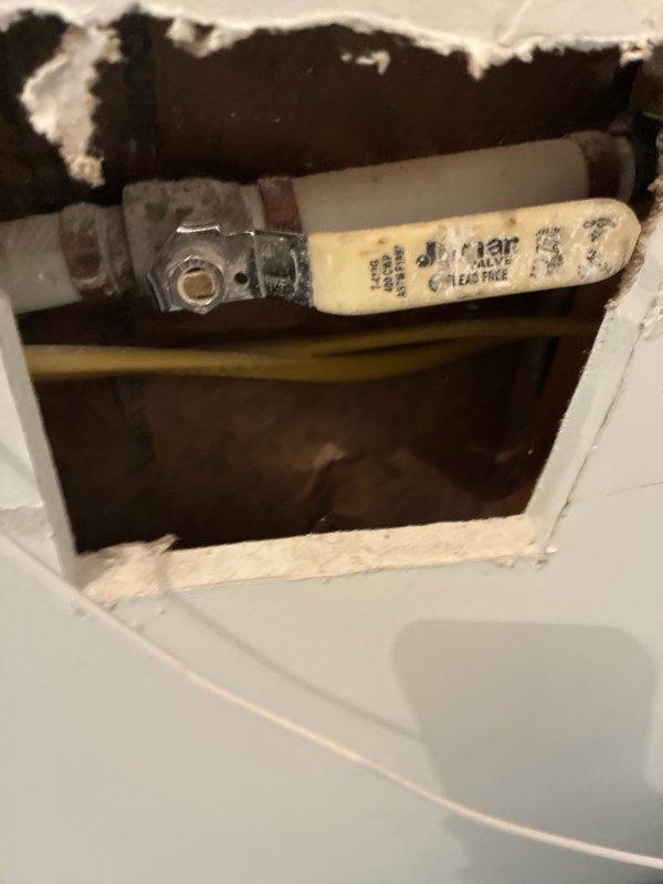 Completed comprehensive whole-home plumbing inspection at customer's request with no reported issues or concerns. Inspection revealed charred and damaged material in ceiling access point near electrical component, indicating potential fire hazard or previous thermal event requiring immediate attention. Documented water supply line connections at wall-mounted outlet box, noting braided flexible supply lines with brass fittings and protective sleeving in good operational condition.