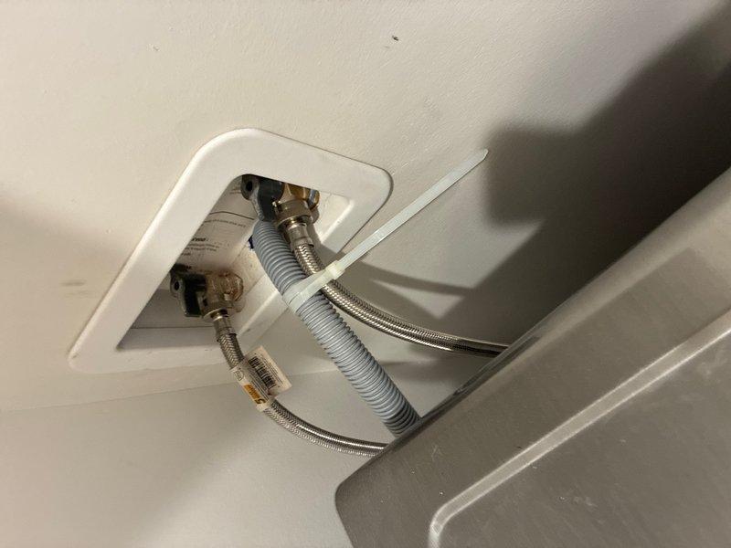 Completed comprehensive whole-home plumbing inspection at customer's request with no reported issues or concerns. Inspection revealed charred and damaged material in ceiling access point near electrical component, indicating potential fire hazard or previous thermal event requiring immediate attention. Documented water supply line connections at wall-mounted outlet box, noting braided flexible supply lines with brass fittings and protective sleeving in good operational condition.