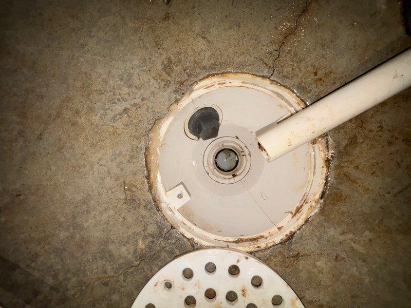 Responded to a clogged floor drain in the electrical room near the furnace that was not draining properly. Upon inspection, found a floor drain with a perforated metal cover and connected PVC piping system showing signs of water backup and moisture damage on the surrounding concrete floor. Removed the drain cover and extracted debris from the drain basin and strainer assembly. Cleared the blockage from the drain line, tested water flow to confirm proper drainage was restored, and reinstalled all components. The drain is now functioning correctly with no standing water present.