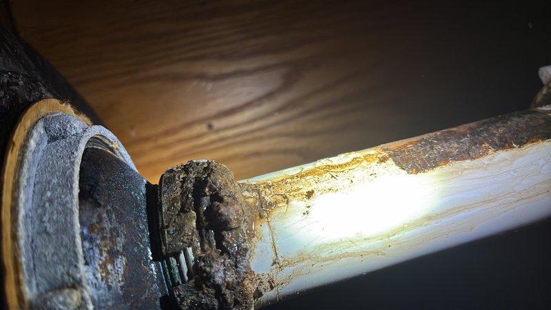 Responded to report of water leaking under kitchen sink. Upon inspection, identified deteriorated PVC drain pipe with significant staining and mineral buildup at connection point beneath sink basin. Replaced damaged section of drain pipe and connection fittings, ensuring proper seal to eliminate leak. Tested drain system for proper flow and verified no additional leaks present. Work completed successfully with system restored to normal operation.